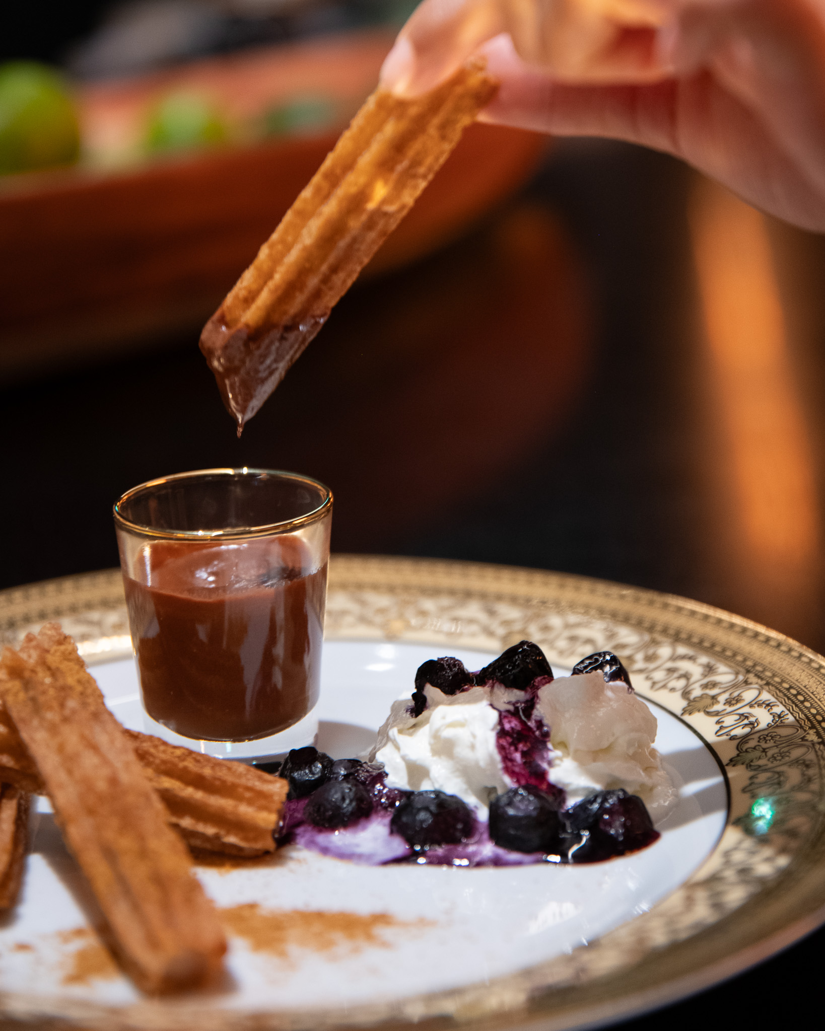Choco Churros being dipped into rich Colombian chocolate with whipped cream and blueberry sauce at A Bunch of Coffee Tokyo